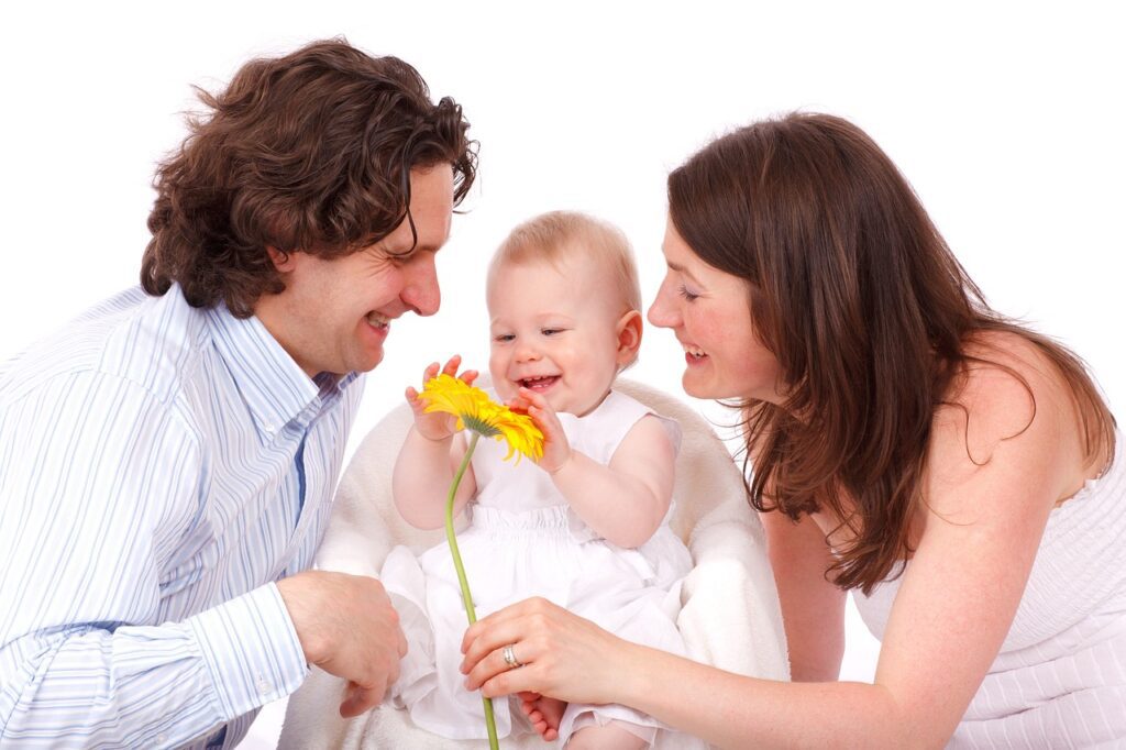 baby holding flower and parents similing