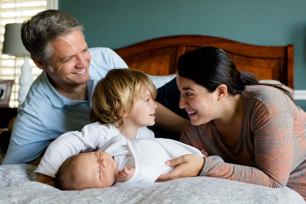 happy family and baby laying on bed